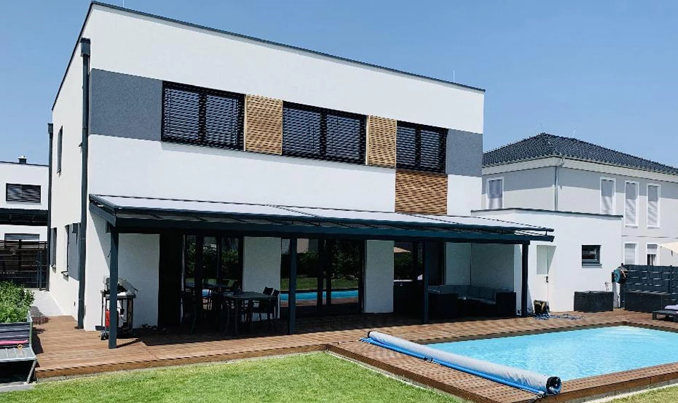 Wintergartenmarkise mit ZIP-Führung Wintergartenmarkise mit ZIP-Führung als Sonnenschutz für Terrasse und Glasdach – moderne Markisenlösung am Einfamilienhaus mit Pool und Holzterrasse.
